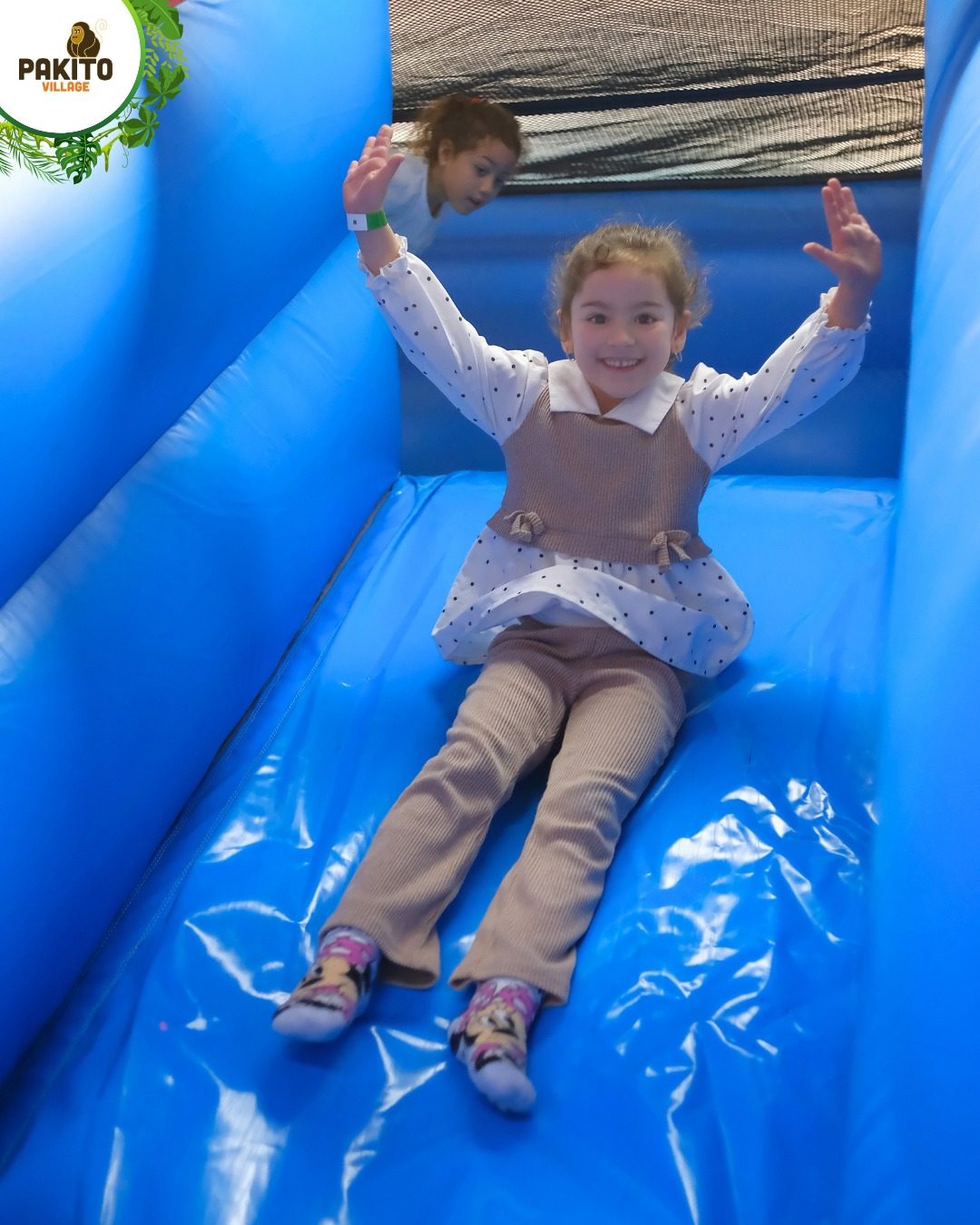 Bambina che scivola su gonfiabile blu al Pakito Jungle Palace